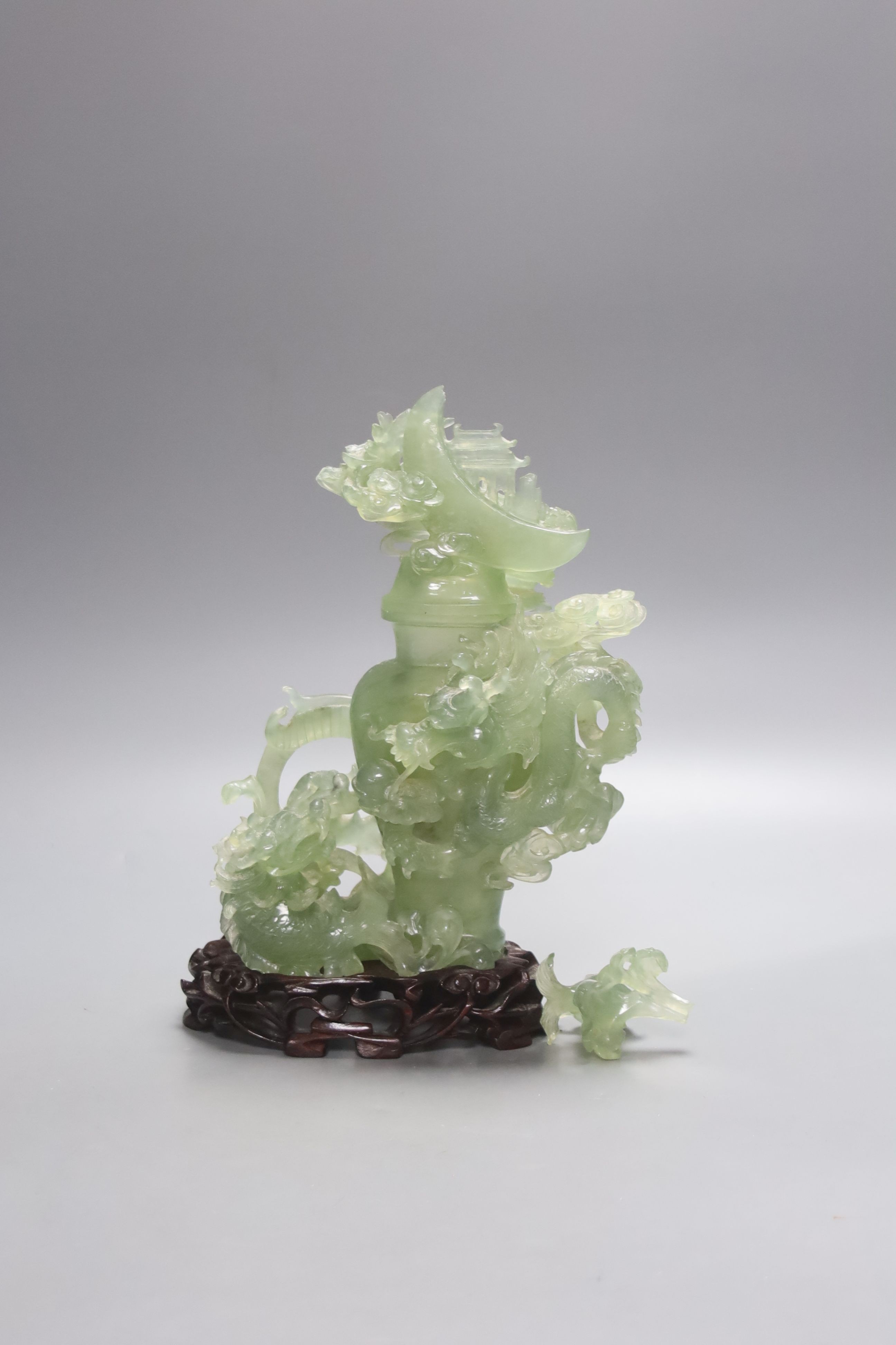 A Chinese green bowenite jade group modelled as a covered urn surrounded by a dragon, H 26cm with carved stand